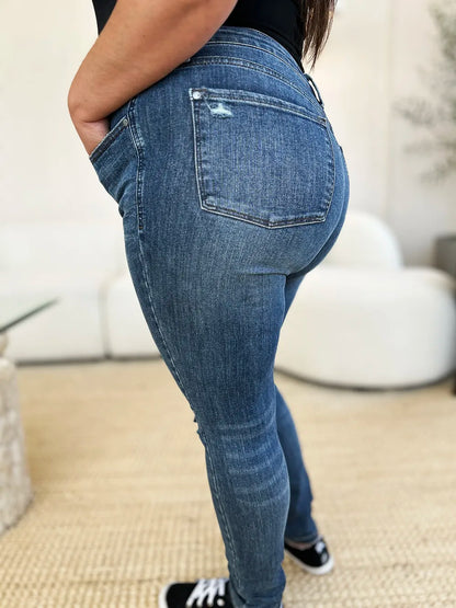 Dark wash Judy Blue full-size mid-waist distressed slim jeans with rips and fading, shown on a model.