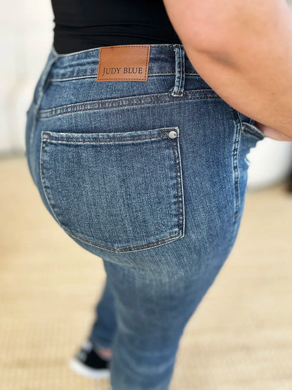Dark Judy Blue full size mid-waist distressed slim jeans with fading and ripped details, shown on a model.