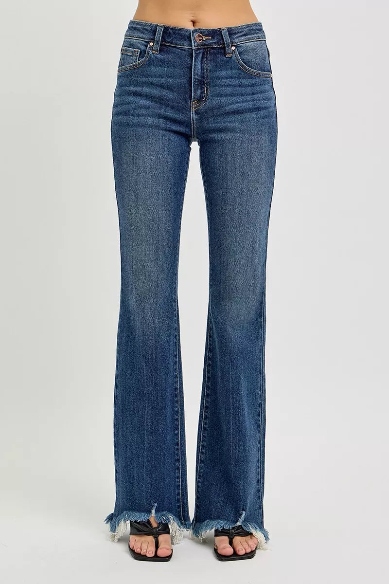 Dark wash Risen plus size flare jeans with mid-rise fit and frayed hem, styled for a casual, trendy look.