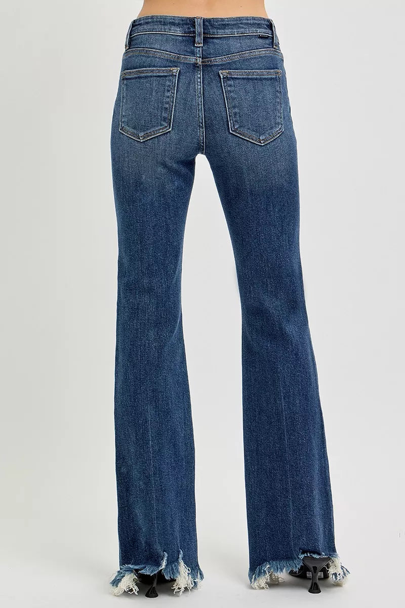 Dark wash Risen plus size mid-rise flare jeans with frayed hem, showcasing a stylish, relaxed fit and trendy denim style.