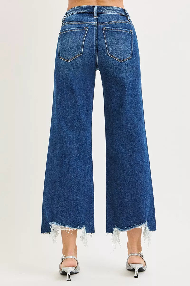 Dark wash Risen high-rise crop wide-leg jeans by Trendsi, showing fit and style on a model with rolled cuffs.
