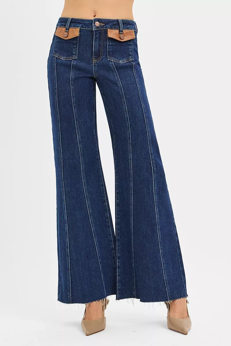 Dark wash RISEN high-rise wide flare jeans with front leather pocket detail, showcasing stylish denim with unique pocket accents.