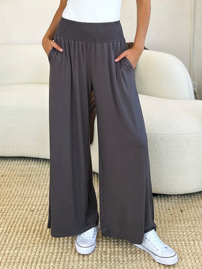 Dark gray Trendsi Basic Bae full-size smocked wide waistband wide-leg pants laid flat, showing relaxed fit and soft fabric.