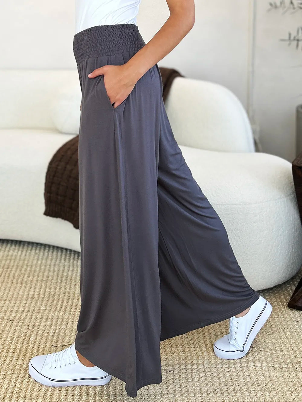 Dark gray Basic Bae full-size smocked wide waistband wide-leg pants from Trendsi, showing the relaxed fit and flowy fabric.