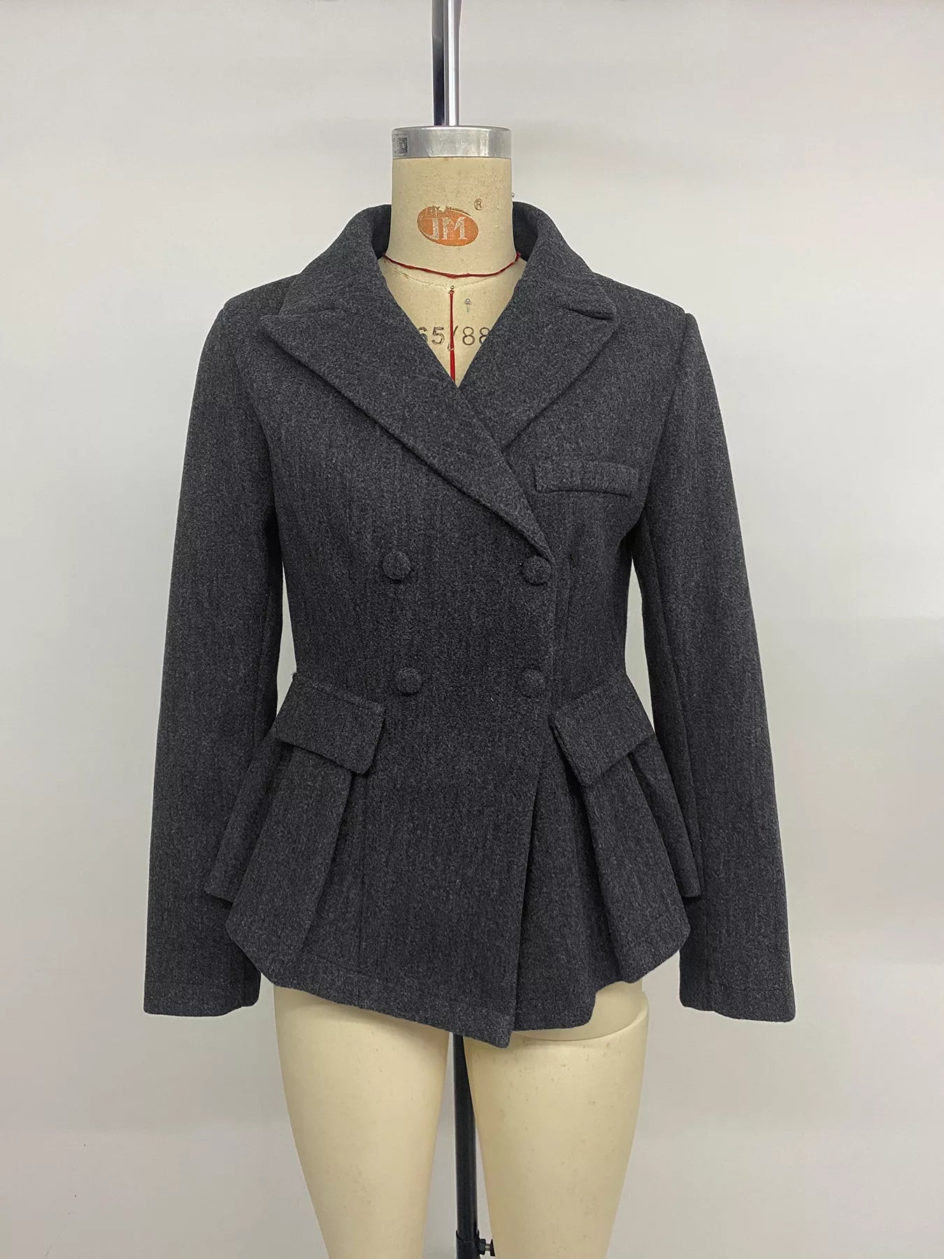 Dark gray Trendsi double-breasted peplum blazer with structured lapels and fitted silhouette, displayed on a hanger.