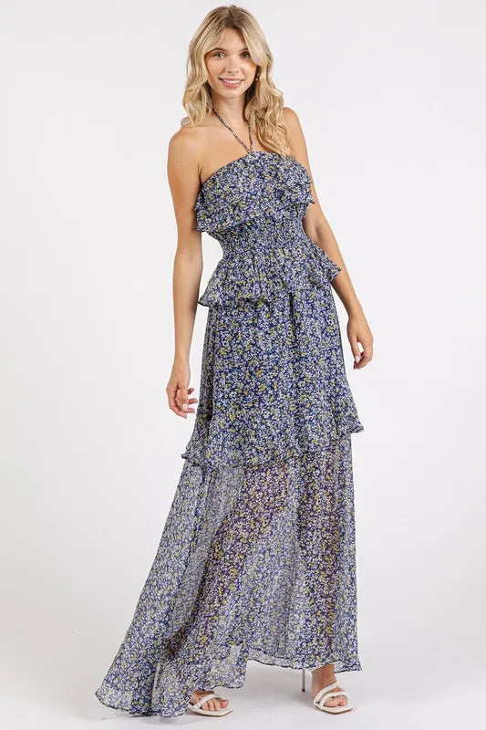 Dark navy Mittoshop ruffled floral smocked halter neck maxi dress by Trendsi, displayed on a hanger with detailed ruffle and floral pattern.
