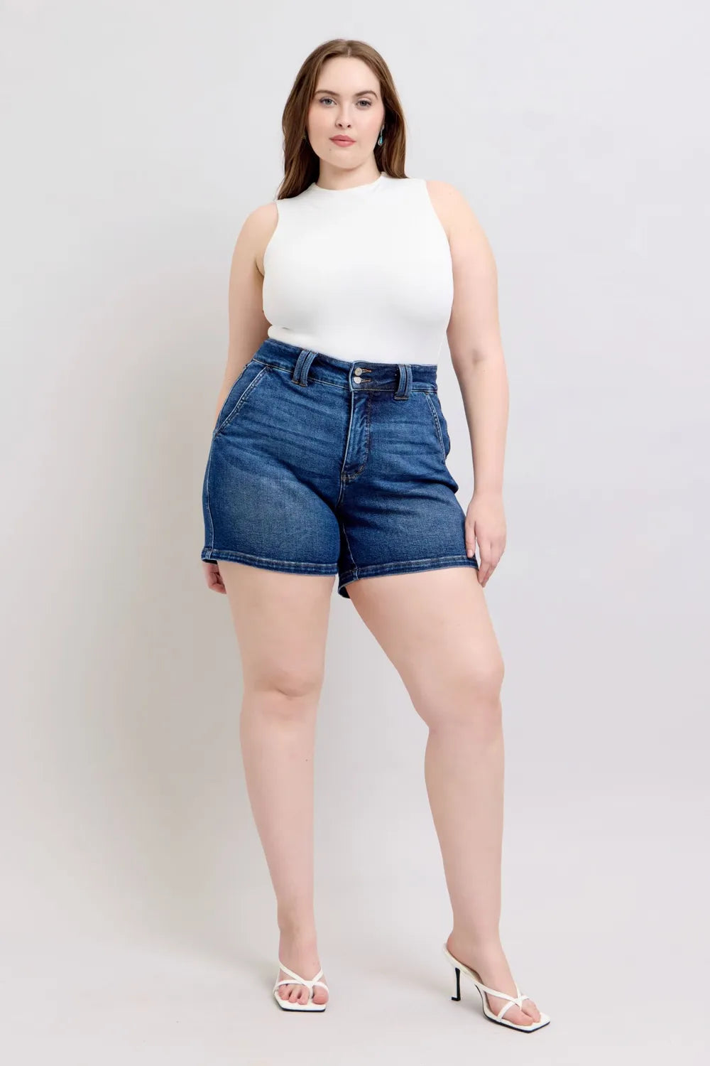 Plus size Judy Blue denim shorts with double button waistband, dark wash, and full-length fit, styled for a casual look.