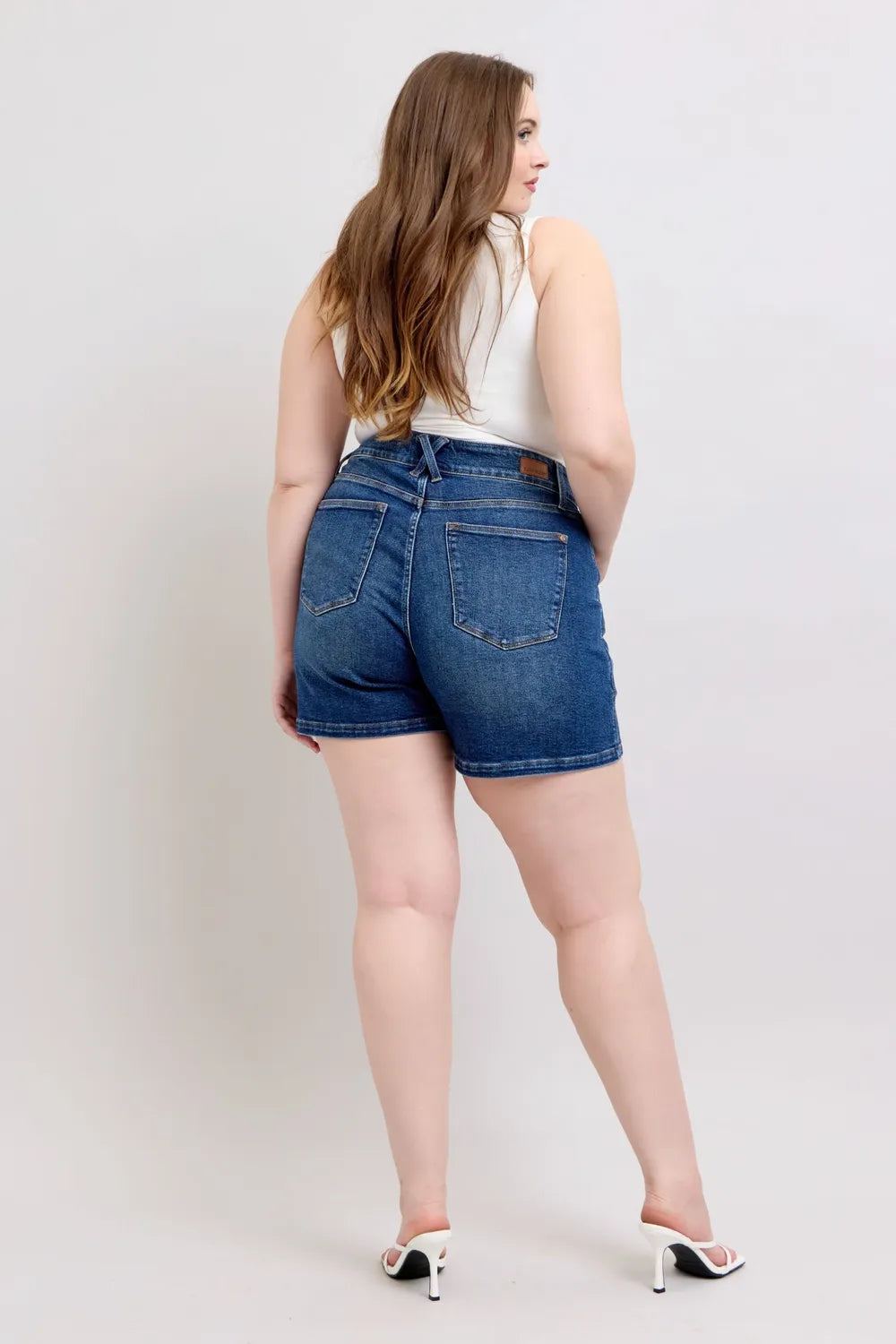 Dark blue Judy Blue plus size denim shorts with double button waistband and relaxed fit, styled for casual wear.