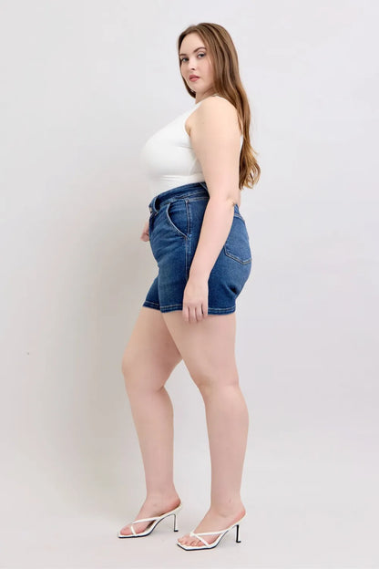 Dark blue Judy Blue plus size denim shorts with double button waistband, full-length cut, styled for a casual look.
