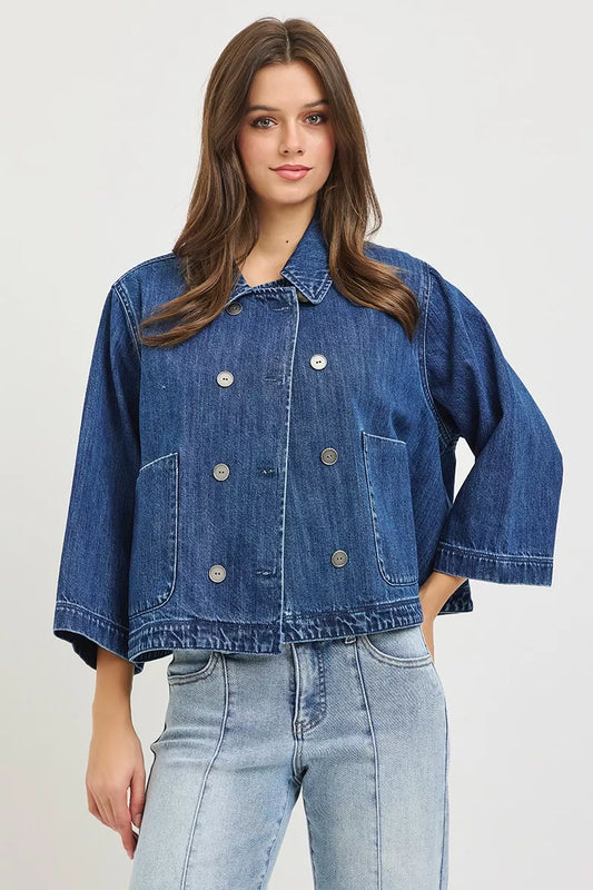 Dark blue RISEN double-breasted flowy cropped denim jacket with long sleeves and classic collar, styled on a model.