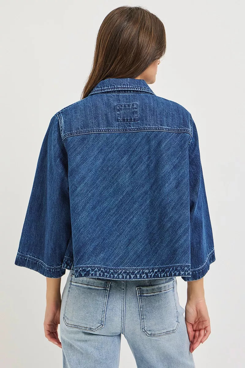 Dark blue Risen double-breasted flowy cropped denim jacket with long sleeves and button details, styled with a casual look.