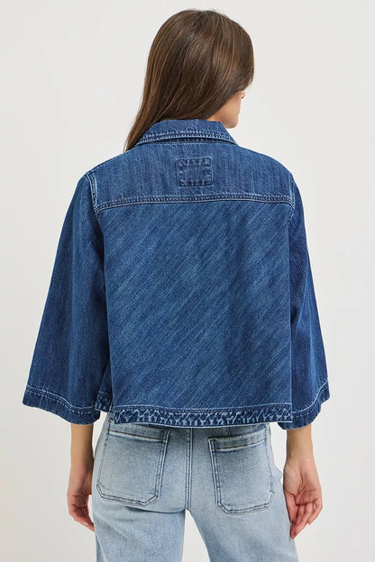 Dark blue Risen double-breasted flowy cropped denim jacket with long sleeves and button details, styled with a casual look.