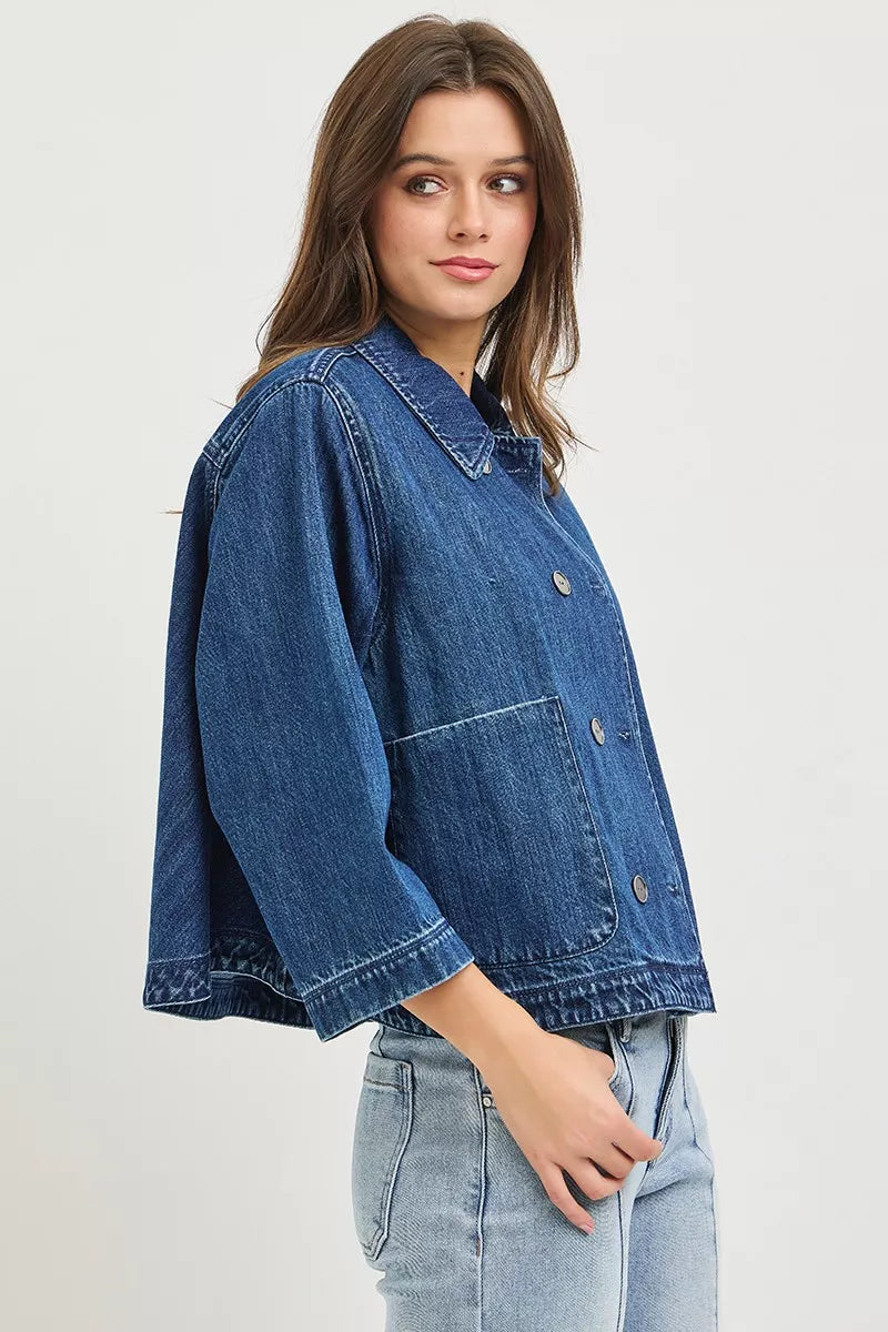 Dark blue RISEN double-breasted flowy cropped denim jacket by Trendsi, shown hanging with front view and rolled-up sleeves.