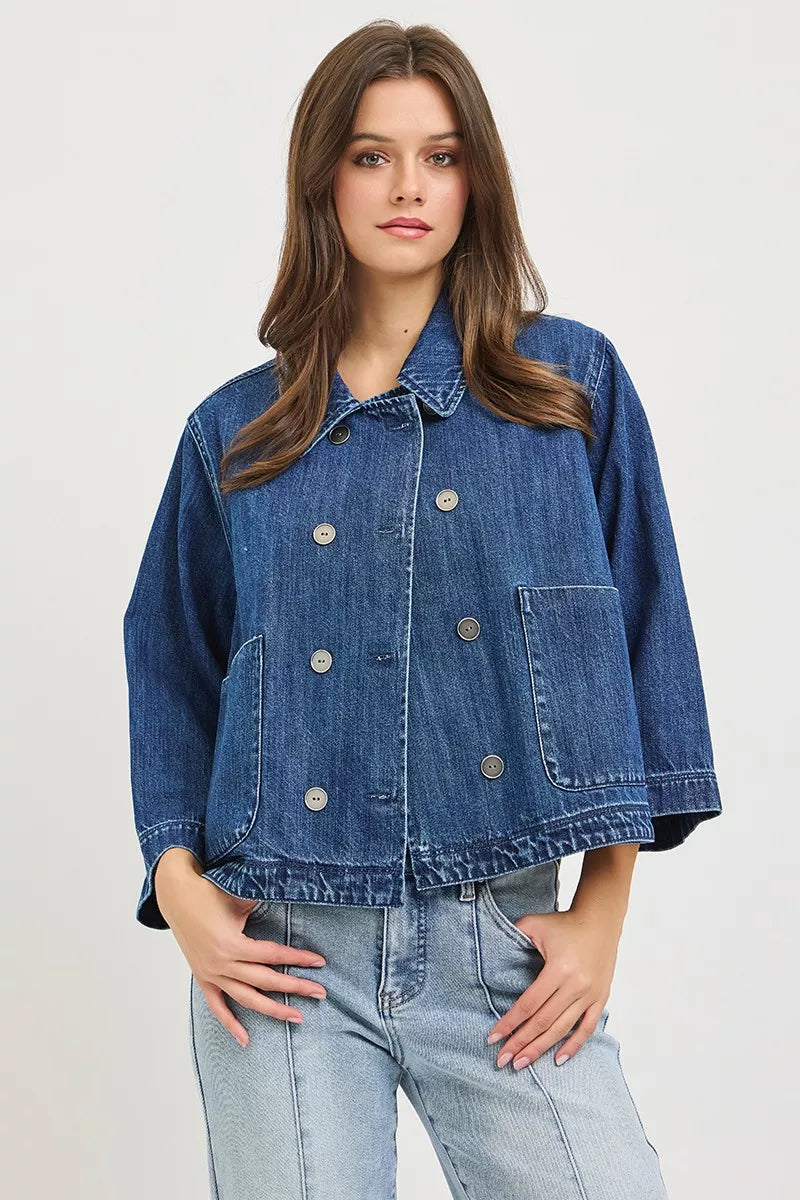 Dark blue RISEN double-breasted flowy cropped denim jacket with long sleeves and classic collar, styled on a mannequin.