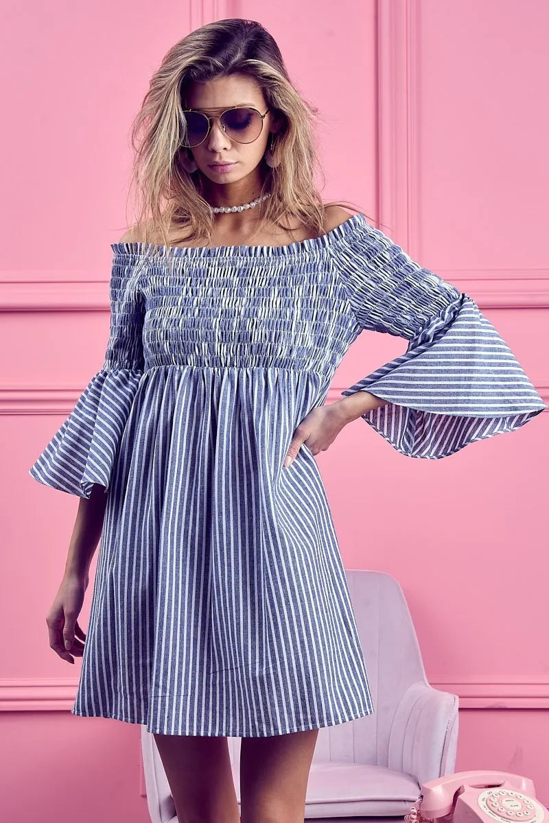 BiBi Smocked Off-Shoulder Striped Dress by Trendsi featuring a fitted bodice and flowing skirt with blue and white stripes.
