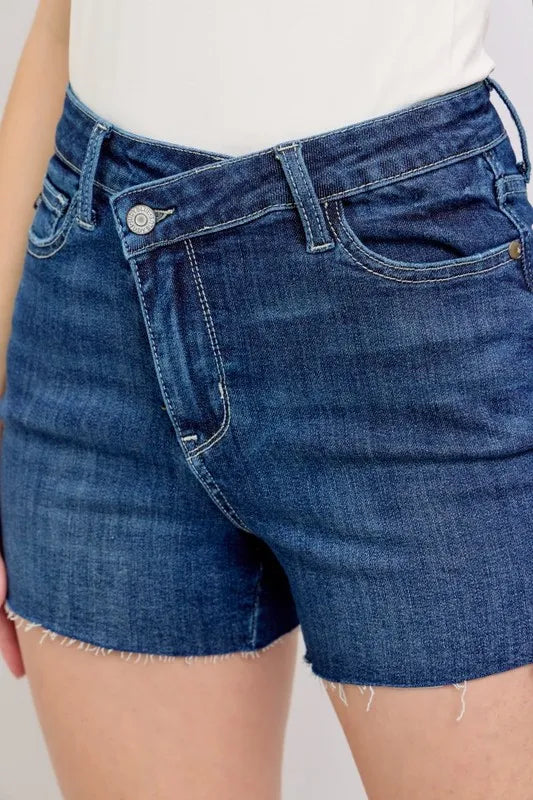 Plus size Judy Blue high waist denim shorts with criss-cross waistband and distressed details, full-length view.