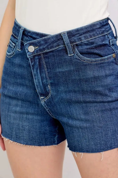 Plus size Judy Blue high waist denim shorts with criss-cross waistband and distressed details, full-length view.