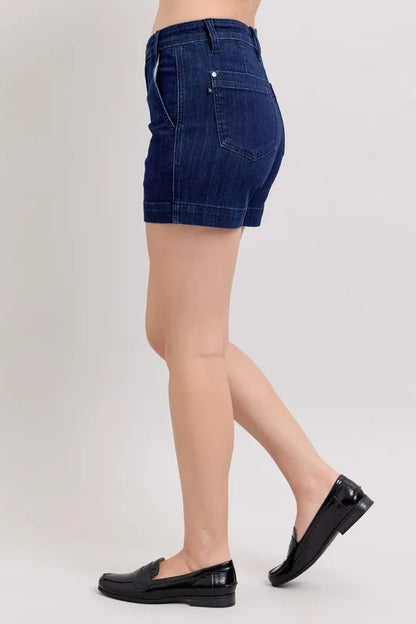 Plus size Judy Blue high waist denim shorts with a classic blue wash, featuring a relaxed fit and stylish rolled hems.