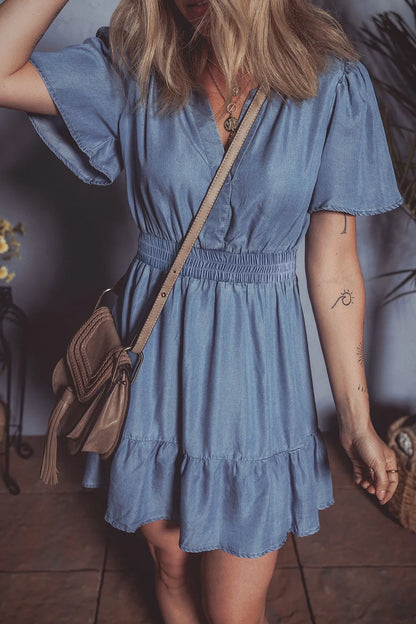 Dusty blue denim mini dress by Trendsi with ruffled hem, smocked waist, and flutter sleeves, perfect for casual summer wear.