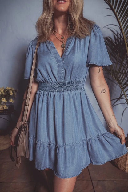Dusty blue denim mini dress with ruffled hem, smocked bodice, and flutter sleeves from Trendsi.