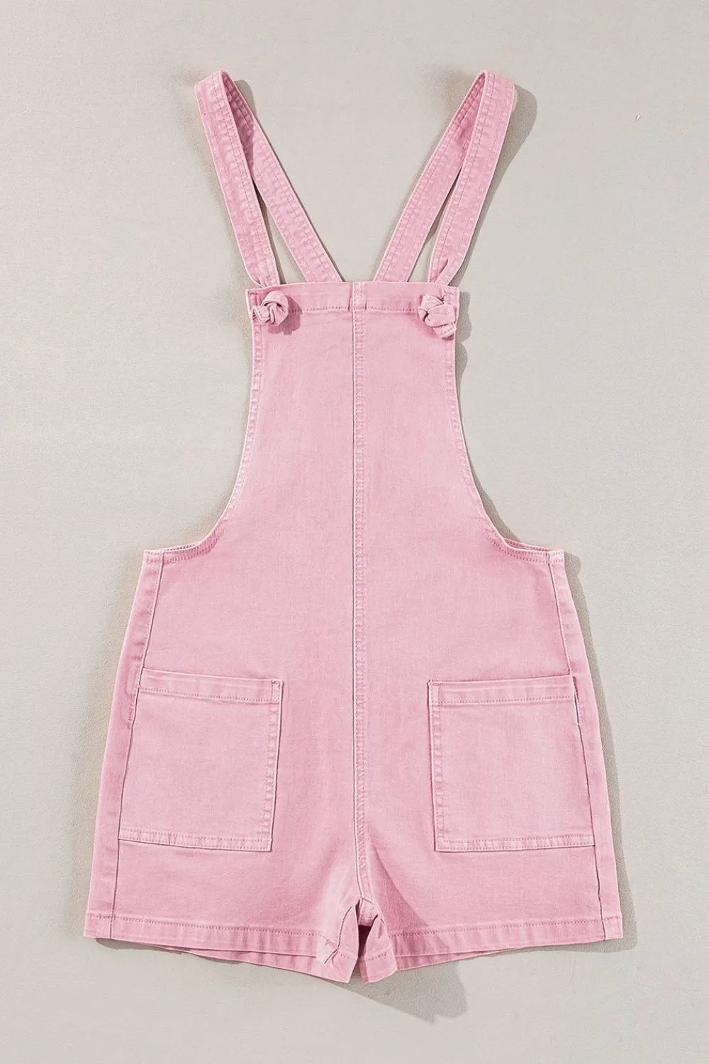 Dusty pink denim overalls with knot straps and front pockets by Trendsi, featuring a casual, relaxed fit.