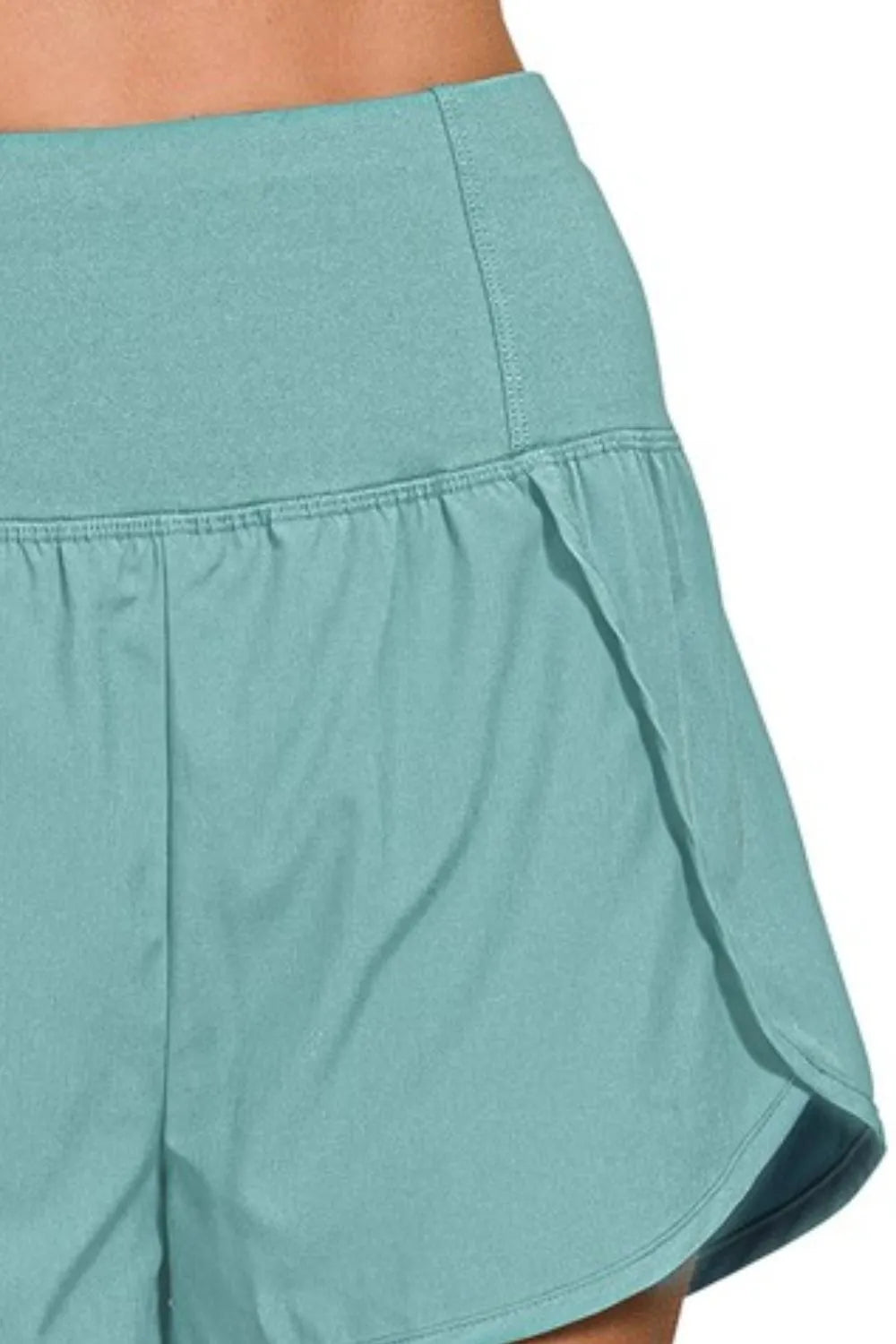 Dusty teal Zenana high-waisted running shorts with zippered back pocket, designed for active wear and comfort.