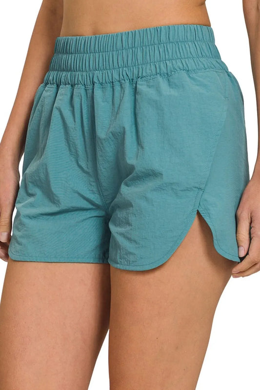 Dusty teal Zenana windbreaker running shorts with smocked waistband, designed for comfort and active wear.