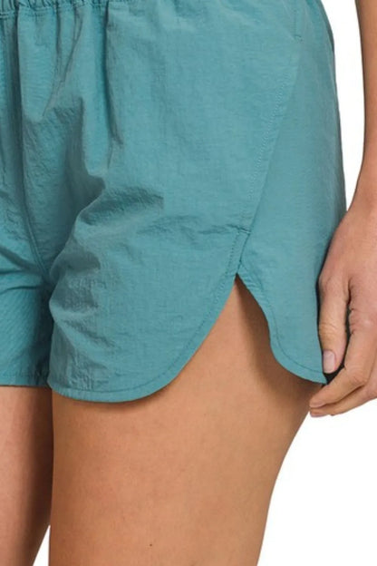 Dusty teal Zenana windbreaker running shorts with smocked waistband, lightweight and comfortable for active wear.