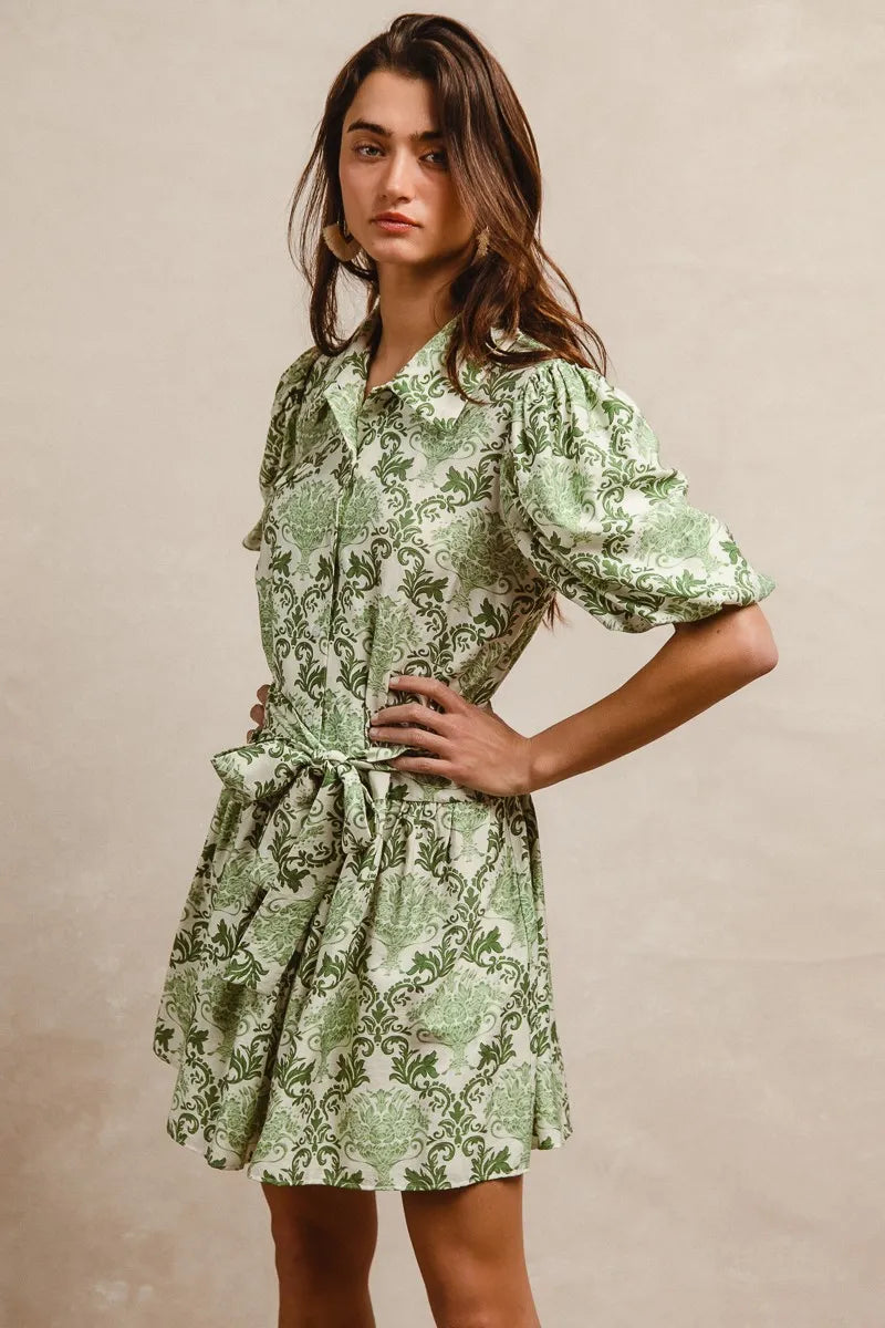 Green and cream floral mini shirt dress with tied waist and short sleeves, by Trendsi, styled on a model.