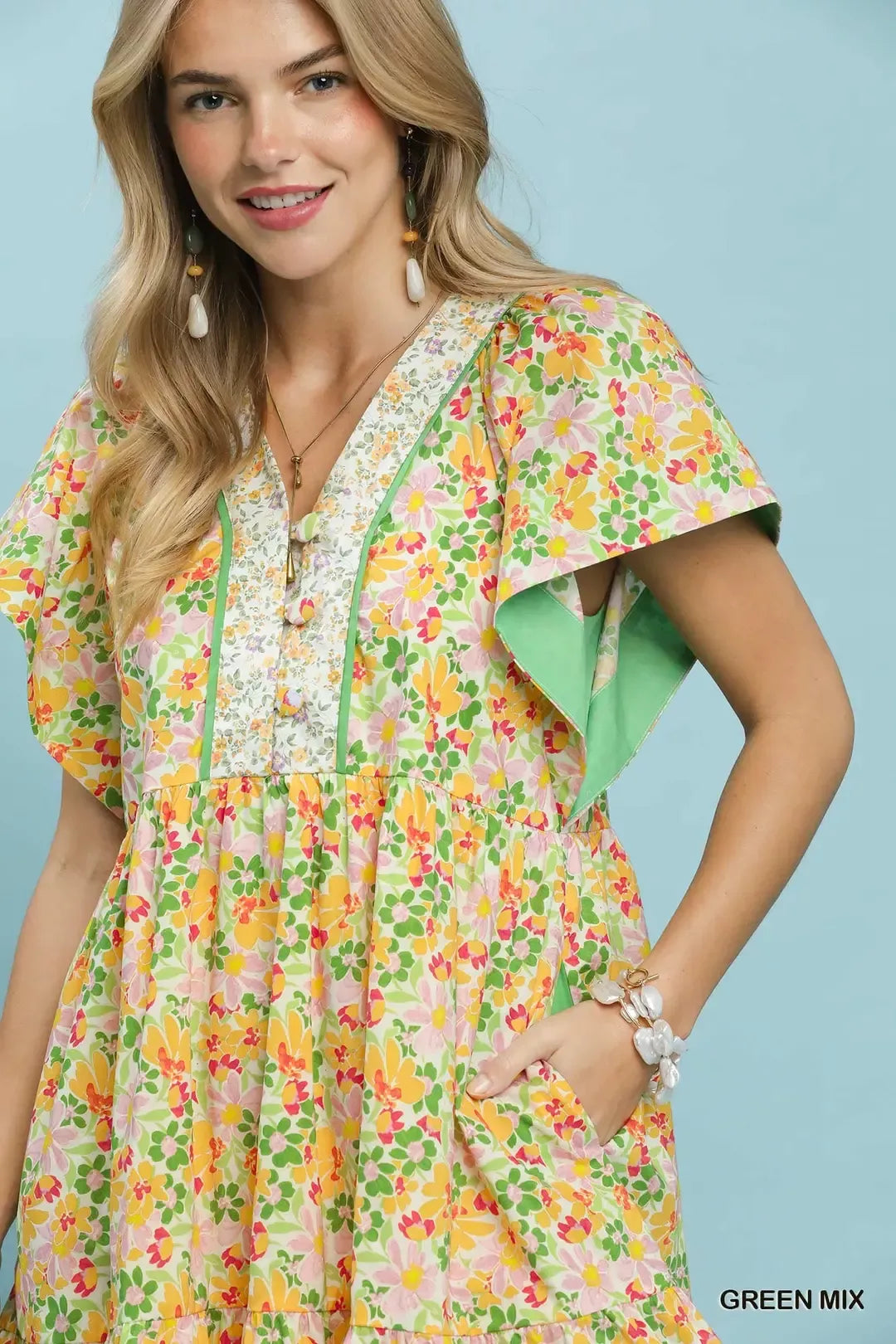 Green floral tiered mini dress by Umgee with side pockets, featuring a mixed floral pattern and casual, breezy style.