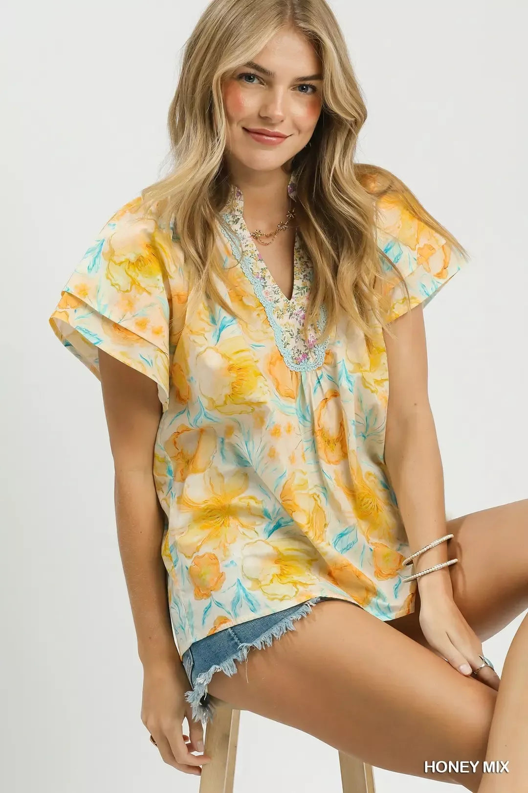 Umgee floral print blouse with crochet lace trim, featuring a mix of vibrant floral patterns and delicate lace details.