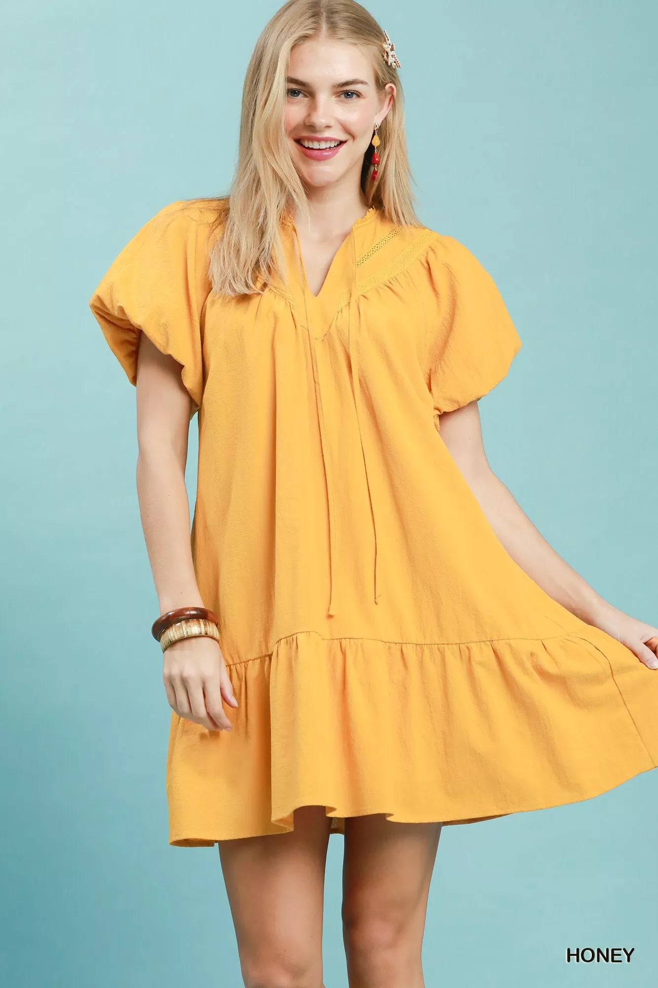 Umgee mini dress with flutter sleeves, tassel tie detail, and ruffle hem, styled in a casual, boho-inspired look