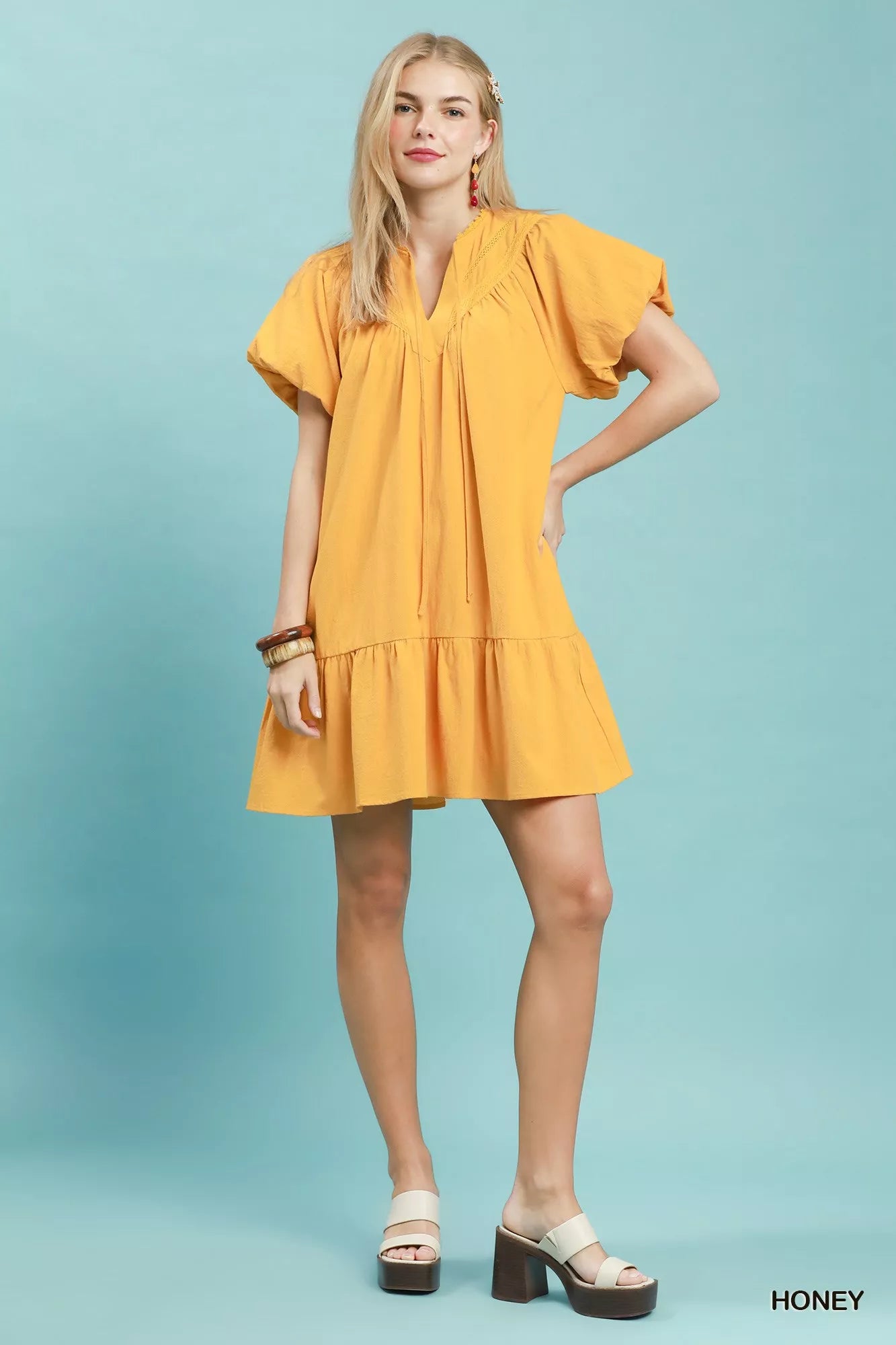 Umgee mini dress with flutter sleeves, tassel tie, and ruffle hem, featuring a stylish, boho-inspired design.