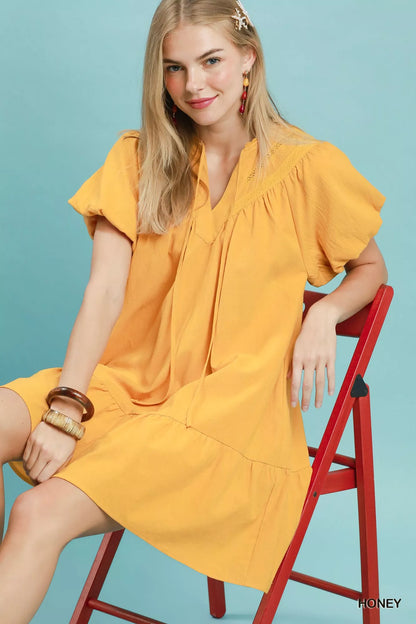 Umgee mini dress with flutter sleeves, tassel tie, and ruffle hem, featuring a stylish, casual design.