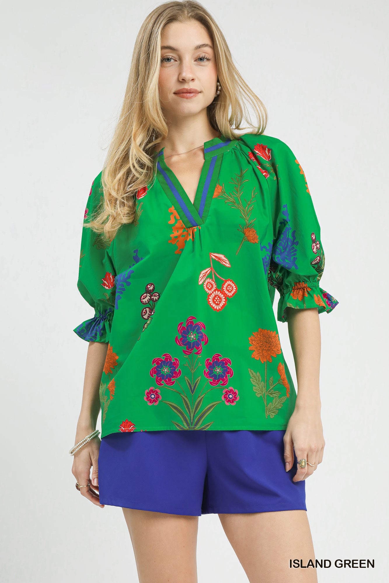 Island green Umgee floral split neck puff sleeve top with ruffled collar and flowy fabric, styled for a casual look.