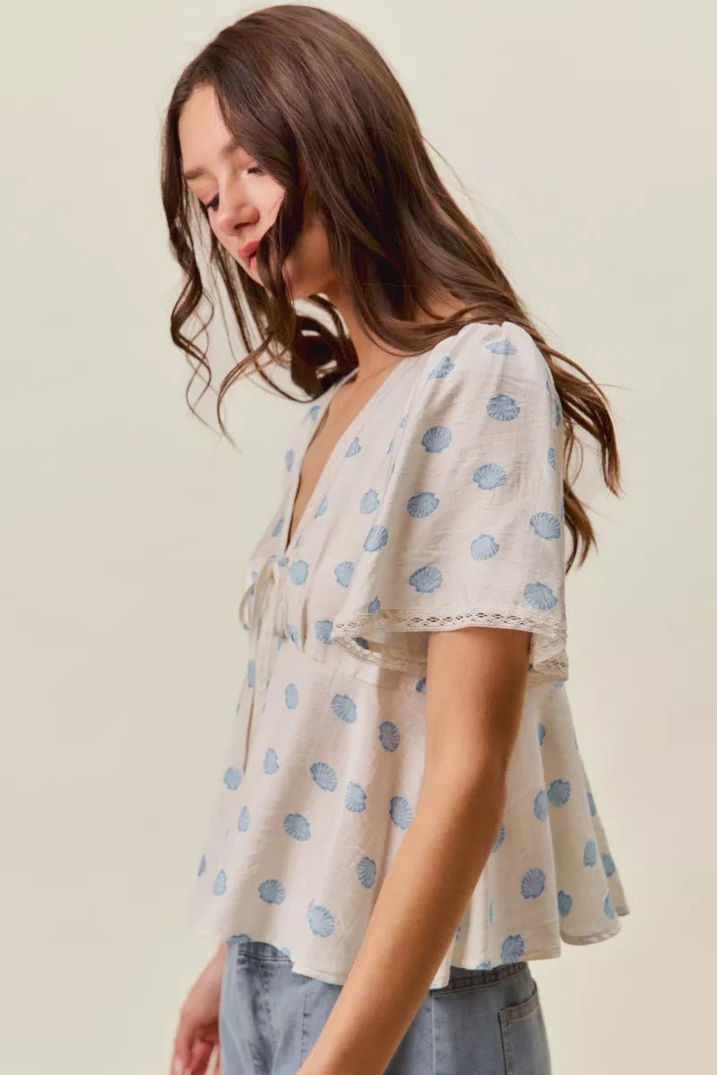 Ivory and blue shell print blouse with tie-front and flutter sleeves, Trendsi women's top for casual or dressy wear.