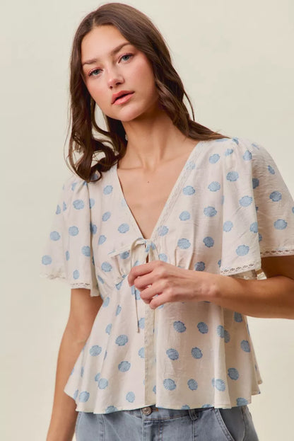 Ivory and blue SO ME shell print blouse top with tie-front and flutter sleeves by Trendsi, displayed on a hanger.