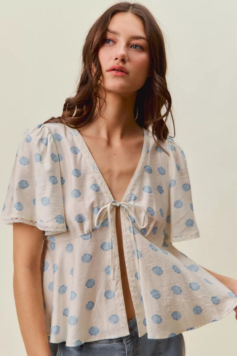 Trendsi ivory and blue SO ME shell print tie-front blouse with flutter sleeves and lightweight fabric.