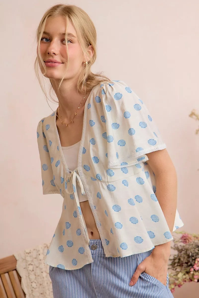 Trendsi ivory and blue shell print tie-front blouse with flutter sleeves and relaxed fit, perfect for casual or stylish outfits.