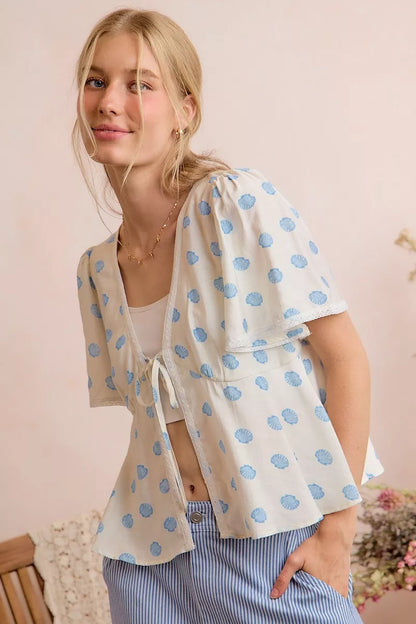 Trendsi ivory and blue shell print tie-front blouse with flutter sleeves and relaxed fit, perfect for casual or stylish outfits.