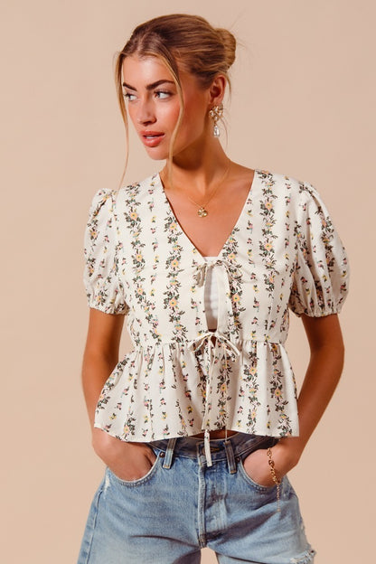 Ivory floral print tie-front blouse by Trendsi featuring a shirred hem and long sleeves, perfect for casual or dressy occasions.