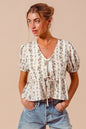 Ivory floral print tie-front blouse by Trendsi featuring a shirred hem and long sleeves, perfect for casual or dressy occasions.