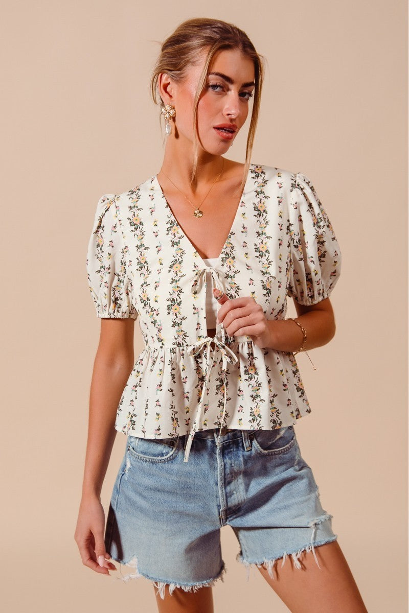 Ivory floral print tie-front blouse with shirred hem from Trendsi, featuring a stylish and feminine design.