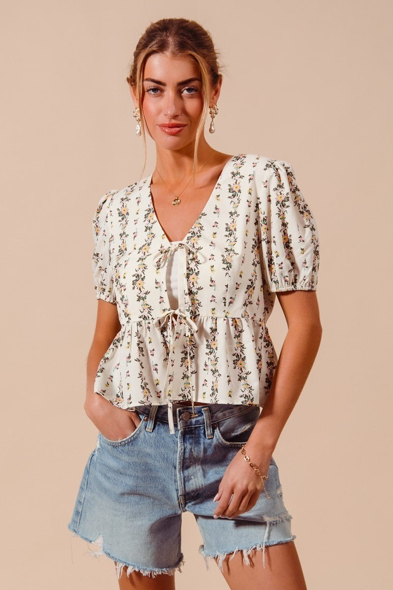 Ivory floral print tie-front blouse with shirred hem from Trendsi, featuring a stylish and feminine design.
