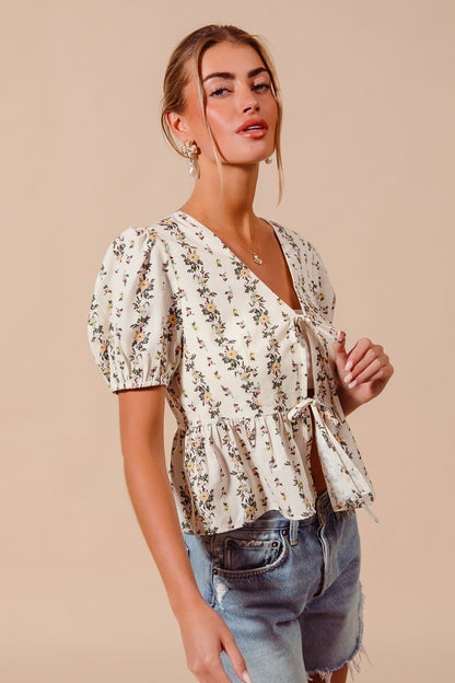 Ivory floral print tie-front blouse by Trendsi featuring a shirred hem and long sleeves, perfect for casual or dressy occasions.