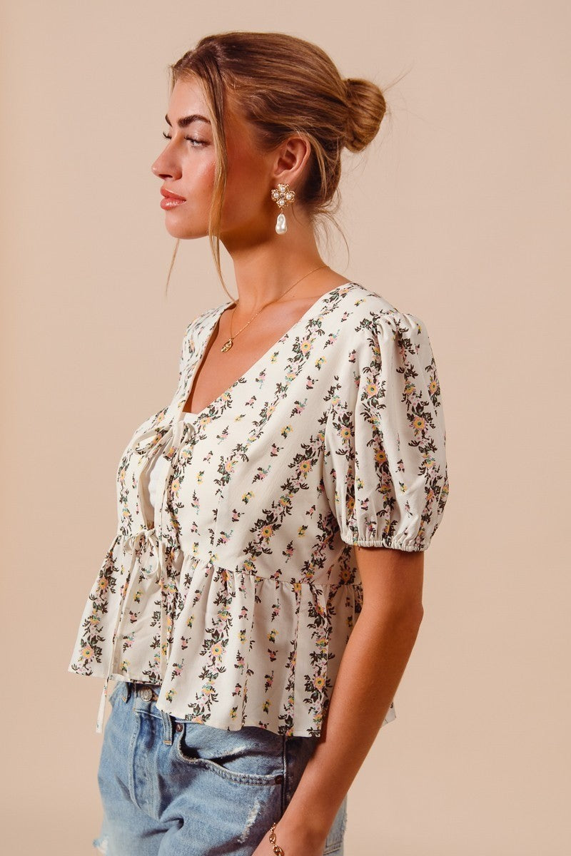 Ivory floral print tie-front blouse by Trendsi featuring a shirred hem and lightweight fabric.