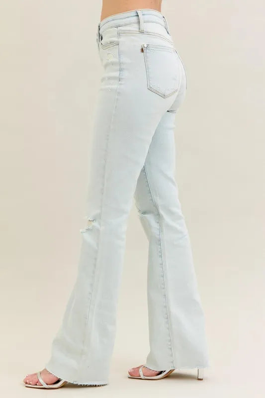 Plus size Judy Blue destroy and fray hem bootcut jeans with distressed details, shown in light wash on a model.