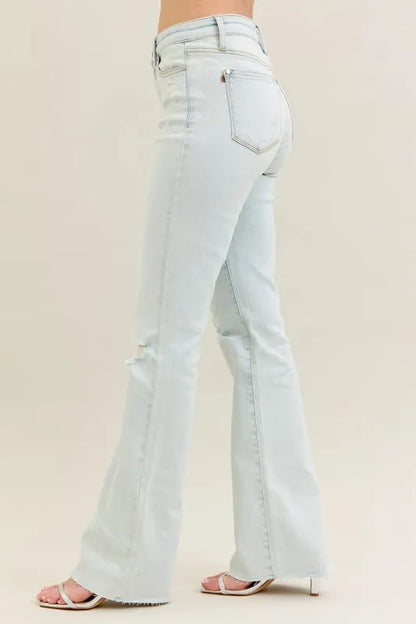 Plus size Judy Blue destroy and fray hem bootcut jeans with distressed details, shown in light wash on a model.