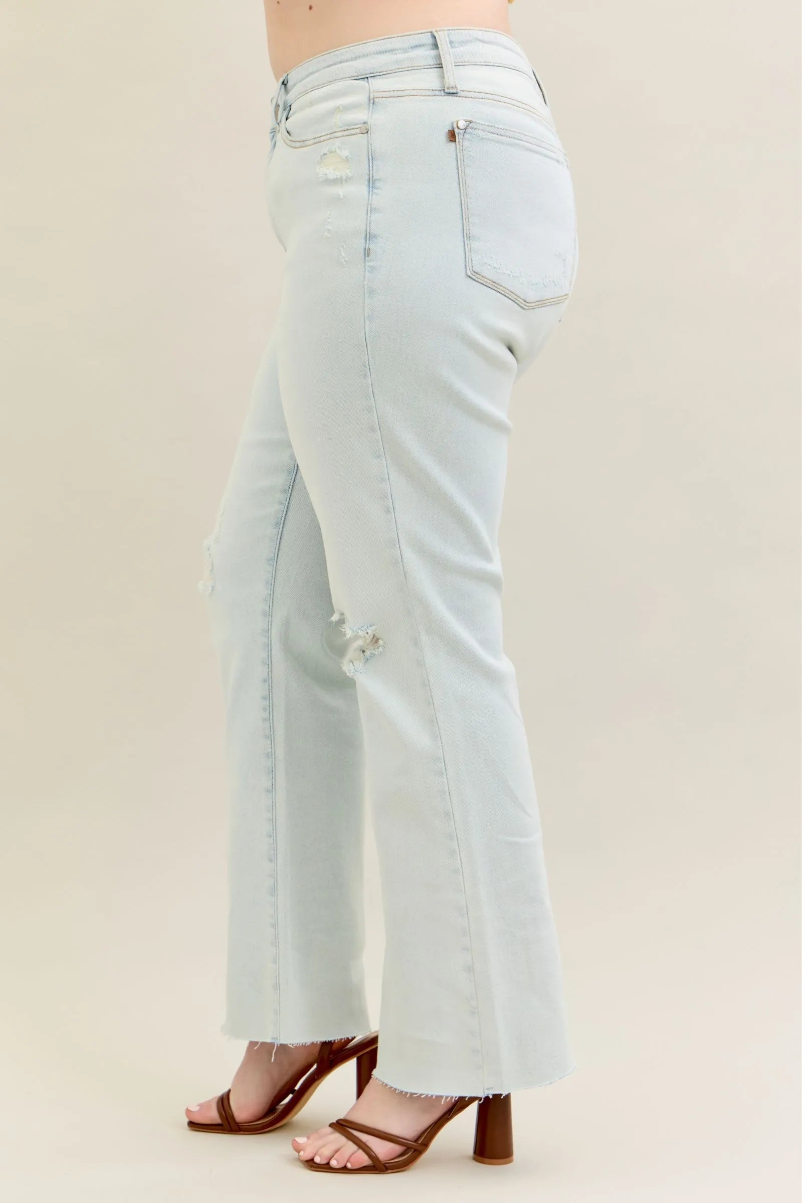 Plus size Judy Blue destroy and fray hem bootcut jeans with distressed details, shown on a model.