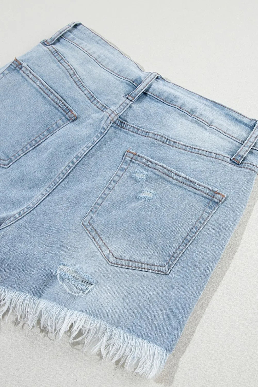 Light blue distressed raw hem high waist denim shorts by Trendsi, featuring frayed edges and classic fit.